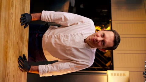 Vertical video a chef in professional kitchen in a white jacket stands leaning Stock Footage 273559128