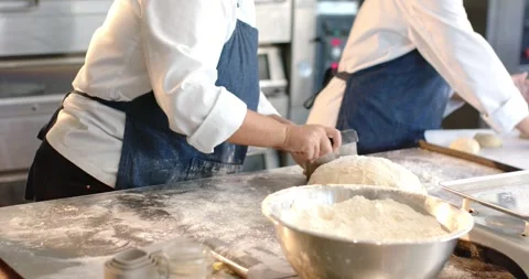 Vertical video: Chefs cutting, weighing, shaping dough mound in bakery aprons Stock Footage 341933055