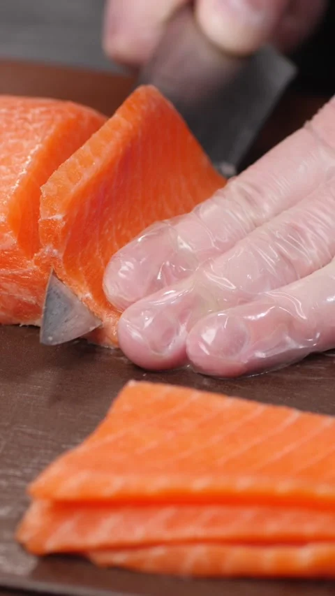 Vertical video. The chef's hand cuts salmon meat into pieces with a knife. Stock-Footage 294393172