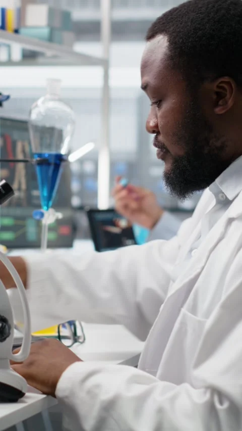 Vertical video Chemical engineer using microscope to evaluate test specimens in Stock Footage 319507078