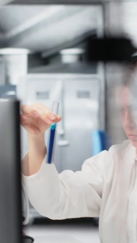 Vertical video Chemist using laboratory glassware with indicator solution next Stockbeeldmateriaal 319593515