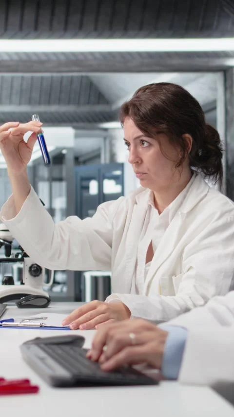 Vertical video Chemist using laboratory glassware with indicator solution next Stockbeeldmateriaal 319594742