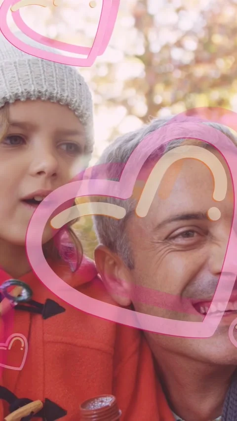 Vertical video: Child blowing bubbles, pink hearts over faces, man holding Stock Footage 337541010