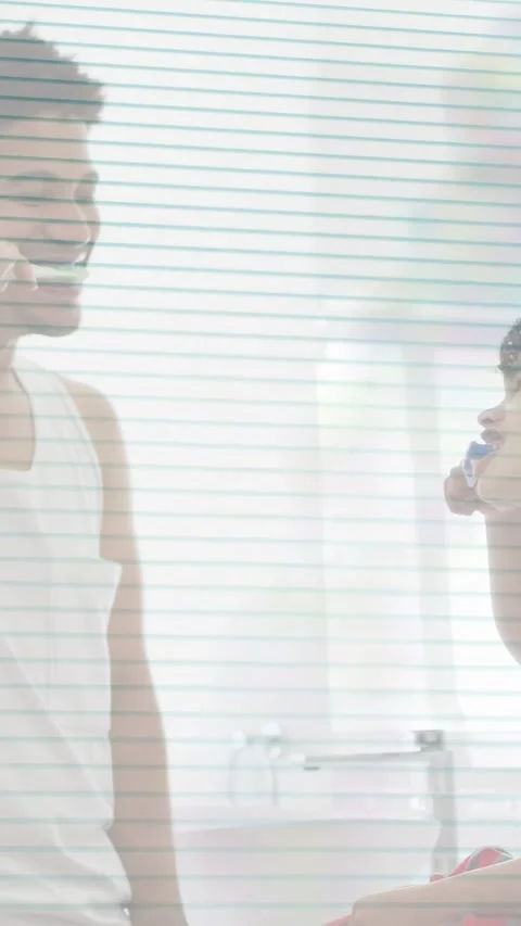 Vertical video: Child on counter brushing teeth, father entering and mirroring Stock Footage 333978252