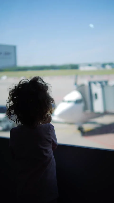 Vertical video of child gazing through a large airport window at the airpla.. Stock Footage 293481345