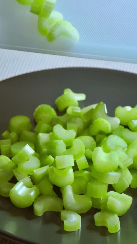 Vertical video, chopped celery stalks are being poured into a plate. Stock Footage 297249941
