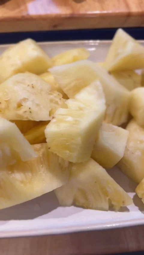 Vertical video of chopped pineapple pieces on white plate Stock Footage 325417415
