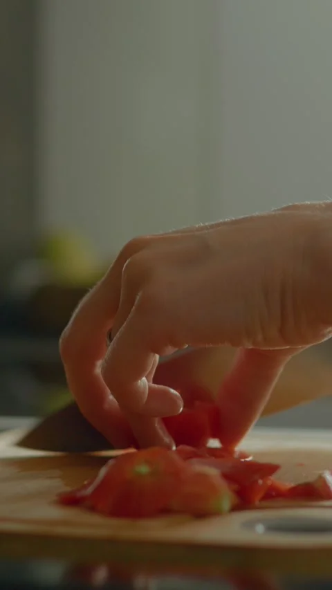Vertical video Chopping fresh tomatoes in the kitchen for a delicious meal Stock Footage 327578188