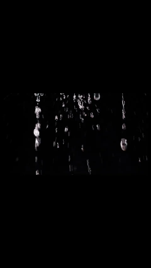 Vertical video. Clear Water Droplets Fall Against an Isolated Black Background, Stock Footage 341413735