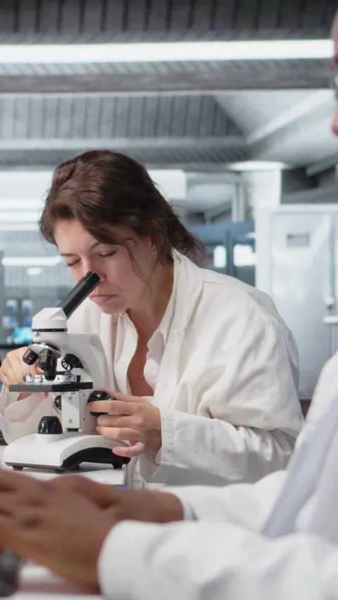 Vertical video Clinical lab technologist uses scientific microscope for disease Stock Footage 319596420