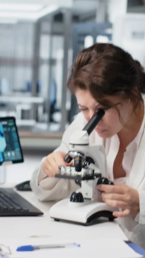 Vertical video Clinical lab technologist uses scientific microscope for disease Stock Footage 319720747