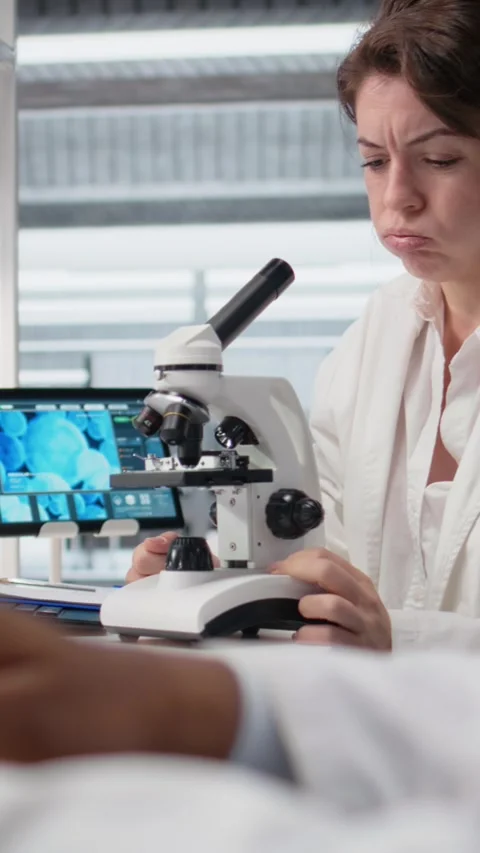 Vertical video Clinical microbiologist in lab adjusting microscope to identify Stock Footage 319506290