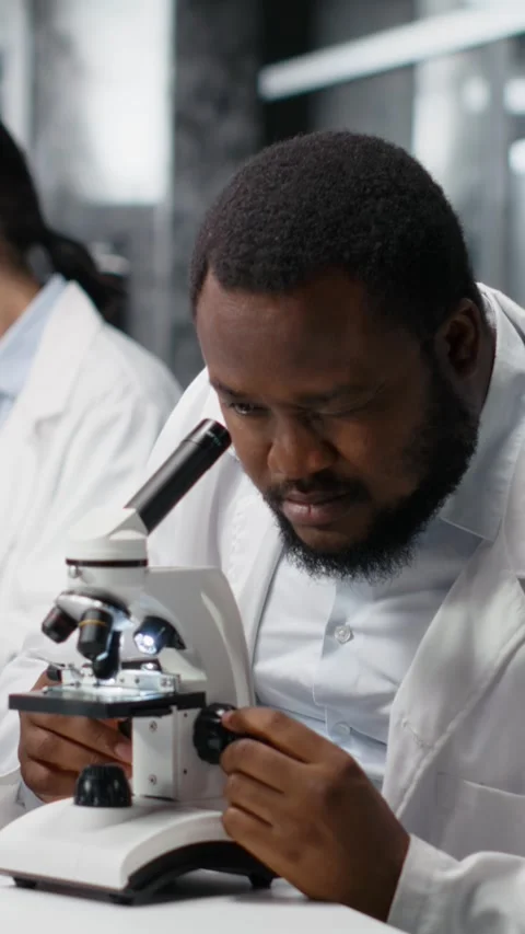 Vertical video Clinical microbiologist in lab using microscope for pathology Stock Footage 319595997