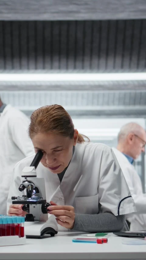 Vertical video Clinical microbiologist using compound microscope for detailed Stock Footage 326366923
