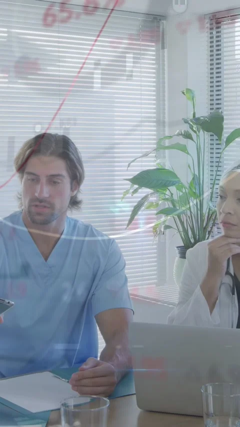 Vertical video: Clinicians analyzing medical data, chart sliding over laptop Stock Footage 332806473