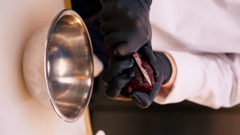 Vertical video close up assistant chef in the kitchen in white jacket cuts beets Stock Footage 273546313