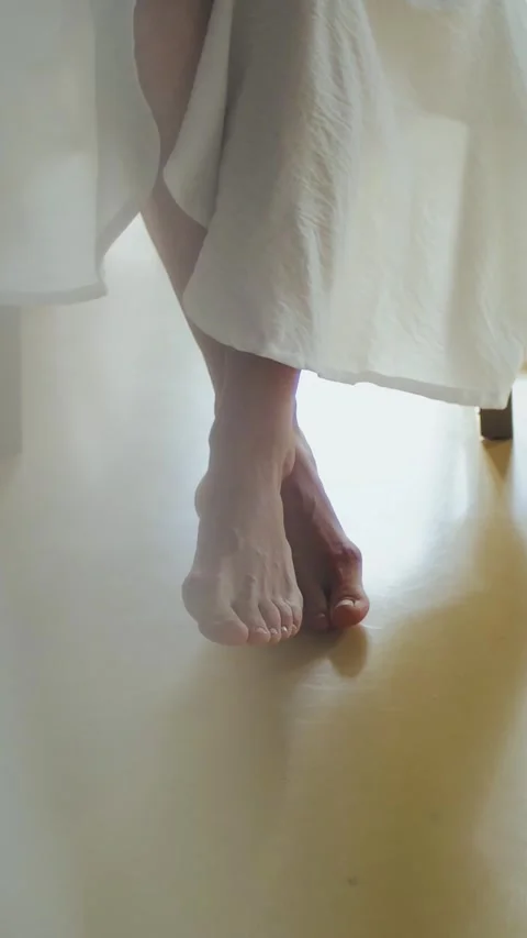 Vertical video. Close-up of bare feet on white floor. Legs crossed. Bride in Stock Footage 311449034