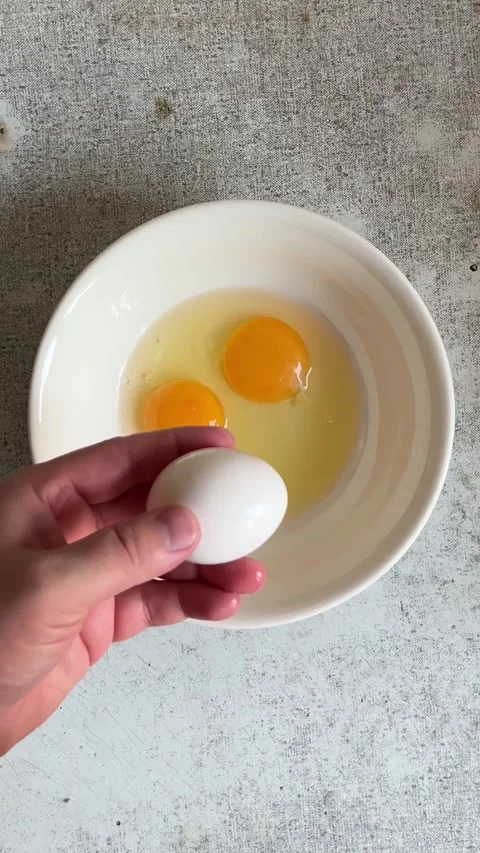 Vertical video close up. Chef with knife breaks chicken egg at kitchen. Top view Video stock 286177722