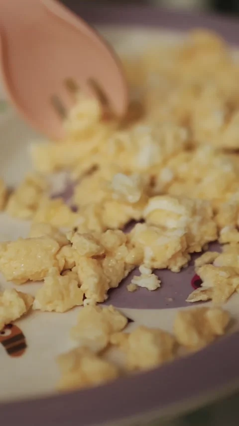 Vertical video. Close-up of a childs hand using a fork to pick up an omelet from Stock Footage 309024759