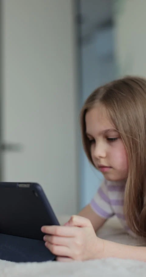 Vertical video. Close-up of a cute little girl using a digital tablet at home Stock Footage 335644153