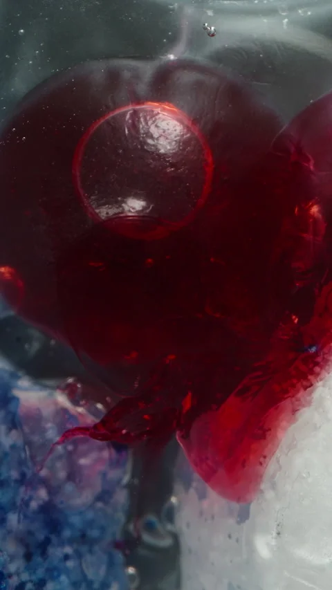 Vertical video. Close-Up of a Dishwasher Tablet Melting, Red and Blue Detergents Stock Footage 283308324