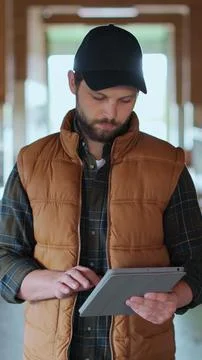 Vertical video. Close up farmer using tablet computer in modern dairy farm fa Stock Photos