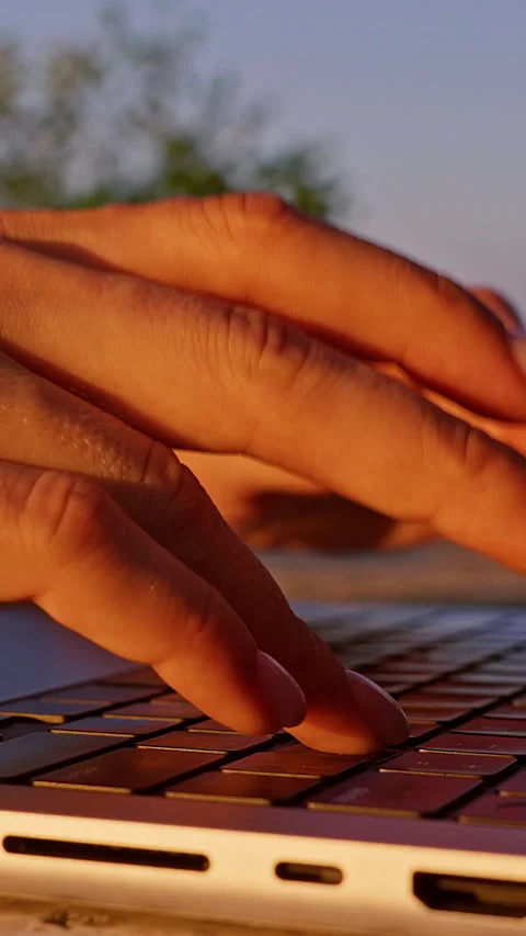 Vertical video. Close Up of Fingers Typing on Laptop Keyboard with Golden Sunset Stock Footage 332304403