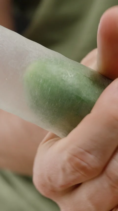 Vertical video. Close-up of a hand holding a cucumber covered with a transparent Stock Footage 301123152