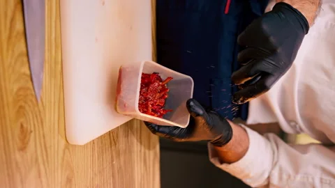 Vertical video close-up of the hands of a chef in a white jacket wearing black Stock Footage 273541768