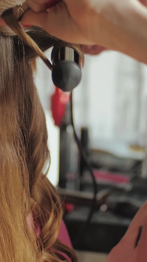 Vertical video. Close-up of hands of professional hairdresser doing curly Stock Footage 311447623