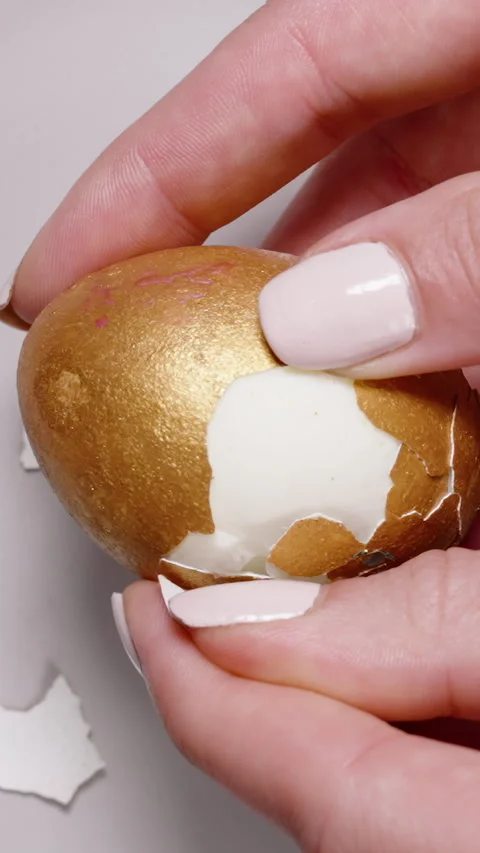 Vertical video. Close-up of hands removing the golden shell from a hard-boiled Stock Footage 295895394