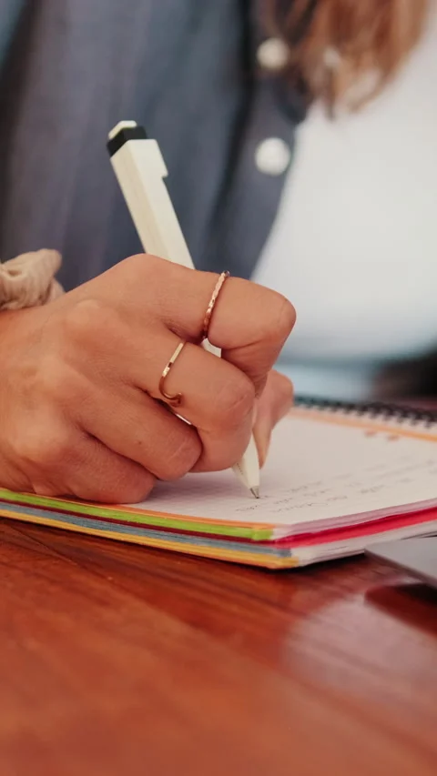Vertical video, Close-up of hands of young woman making notes in notebook Stock Footage 302116225