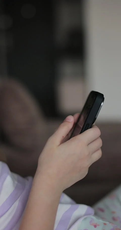 Vertical video. Close up little child girl using mobile phone at home. Stock Footage 335643602