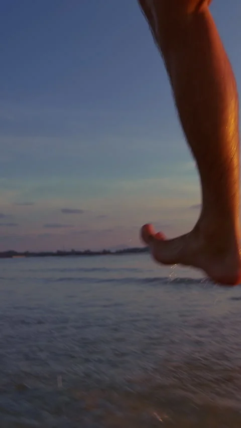 Vertical video. Close Low Angle Dynamic View Of Male Feet Mid Step Above Wet San Stock Footage 331874841
