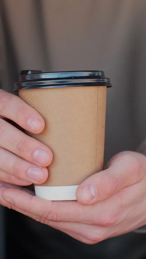 Vertical video. Close up male hand barista giving cup of coffee to camera Видео 344107699