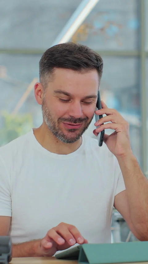 Vertical video. Close up of man barista in coffee shop accepts a pre-order Видео 343770930