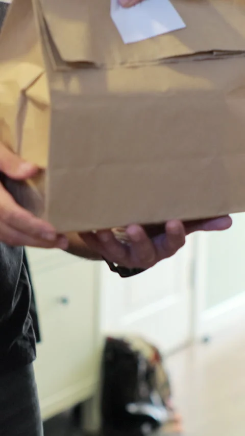 Vertical video. Close up Man opens door to food delivery woman taking order Stock-Footage 344373101