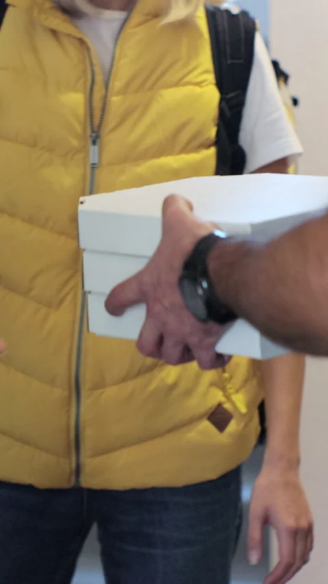 Vertical video. Close up man opens doors and meets pizza delivery woman Видео 344373481