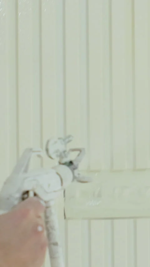 Vertical video. Close up of man painter paints the walls with paint spray gun 動画素材 347154647