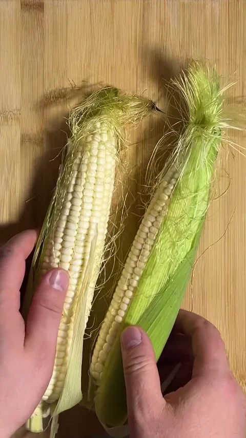 Vertical video close up. Man places cob of corn on wooden cutting board Stock Footage 286177018