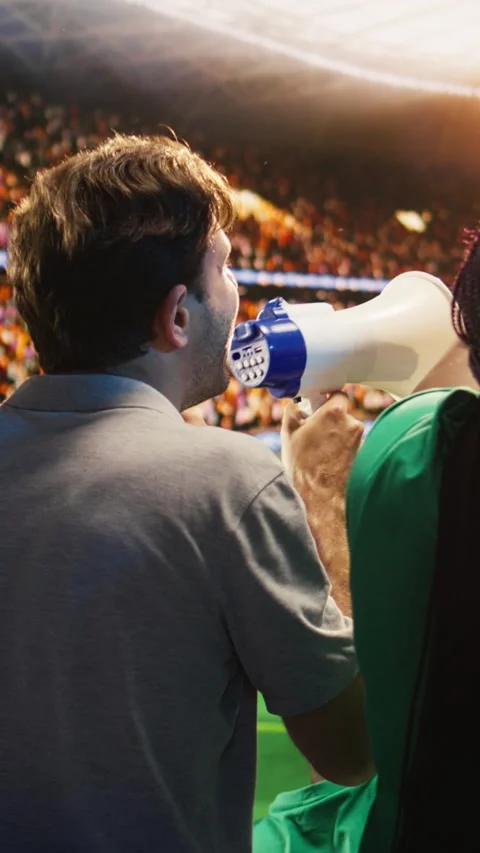 Vertical video Close up of man yelling through megaphone in soccer stadium to Video stock 341678807