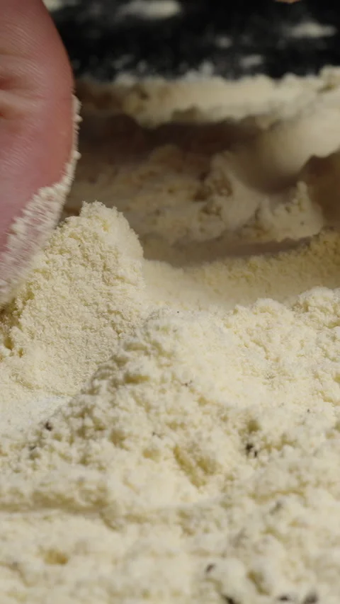 Vertical video. A close-up of a man's hand scooping flour with the eggs of Stock Footage 283305584