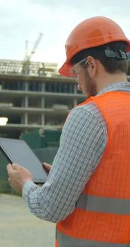 Vertical video. Close-up portrait of engineer with gadget on background of bu Stock Photos