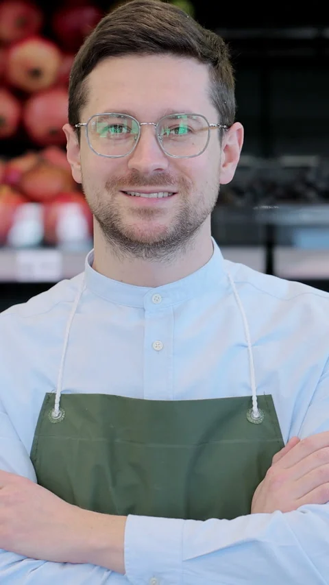 Vertical video. Close up portrait of happy man worker in glasses wearing apron Stock Footage 346684484