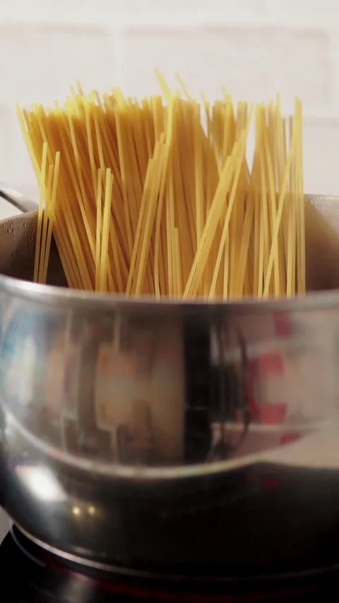 Vertical video close up of raw spaghetti standing upright in stainless steel pot Stock Footage 345212191