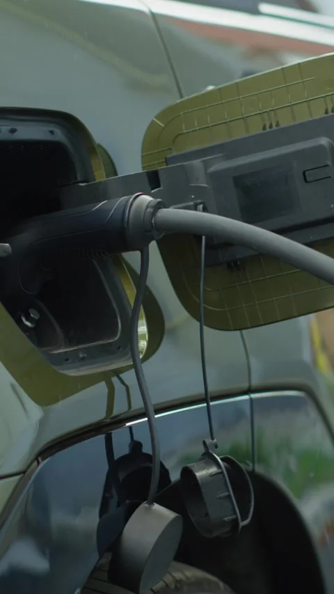 Vertical video Close up shot of EV plug connected to electric car, concept of Stock Footage 315999159