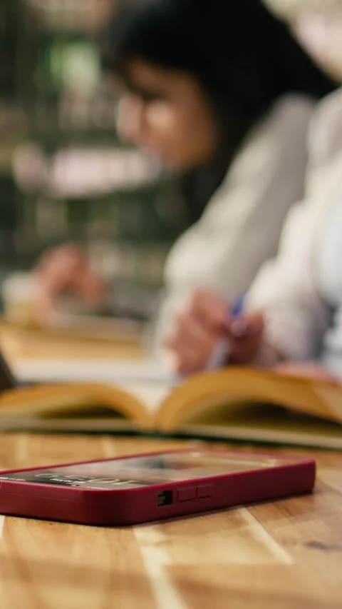 Vertical Video Close up of student using laptop at desk and receives phone Stock Footage 336379150