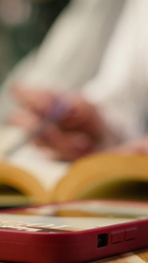 Vertical Video Close up of student using laptop at desk and receives phone Stock Footage 336380240