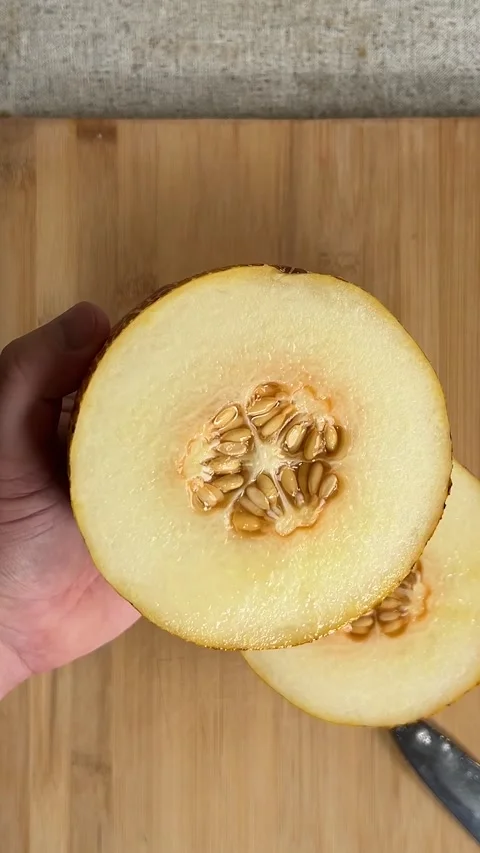 Vertical video close up. Top view. Man shows half fresh juicy yellow melon Stock Footage 286176990