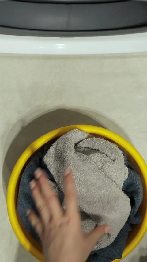 Vertical video. Close-up, top view. Woman loads the washer with dirty laundry Vídeos de archivo 347579084